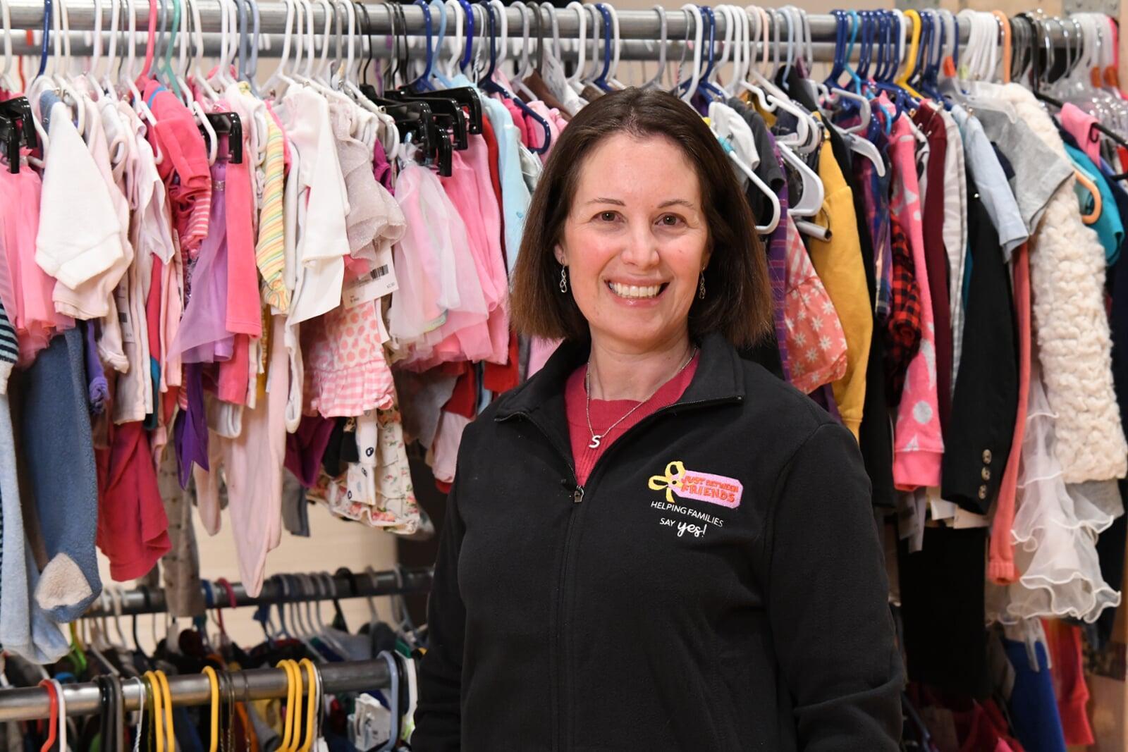A mom and her three kids stand in front of a rack of girls clothes at their local BF sale.