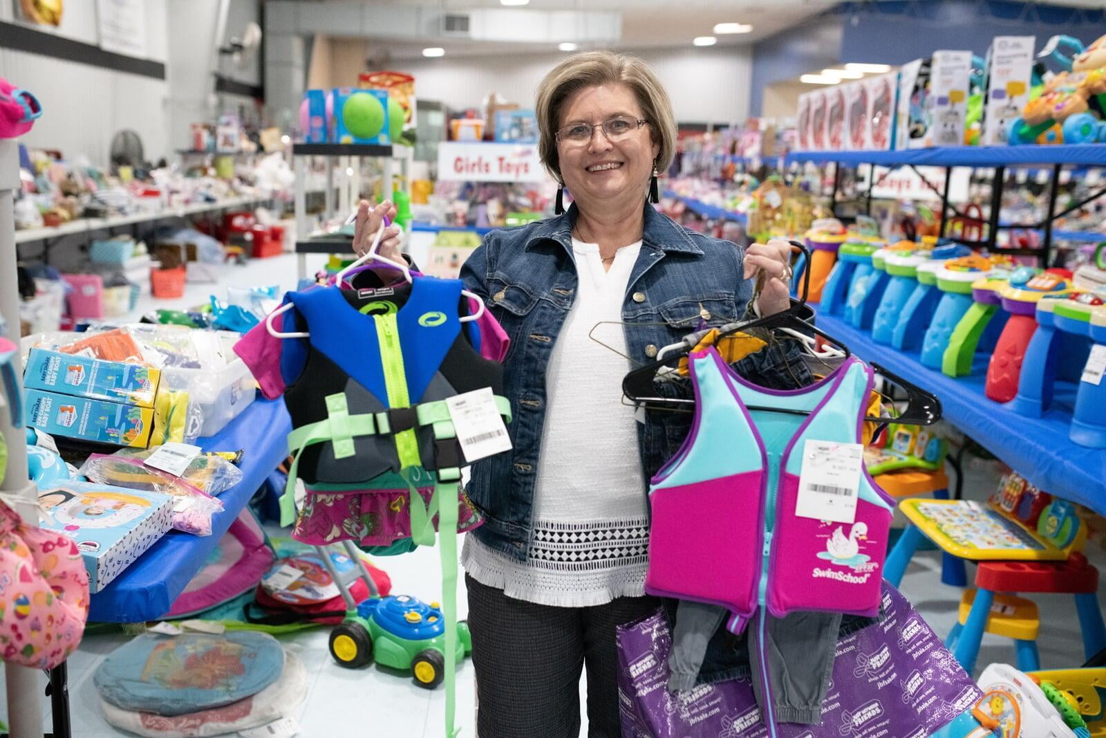 A grandma hold up 2 youth life jackets she finds while shopping JBF!