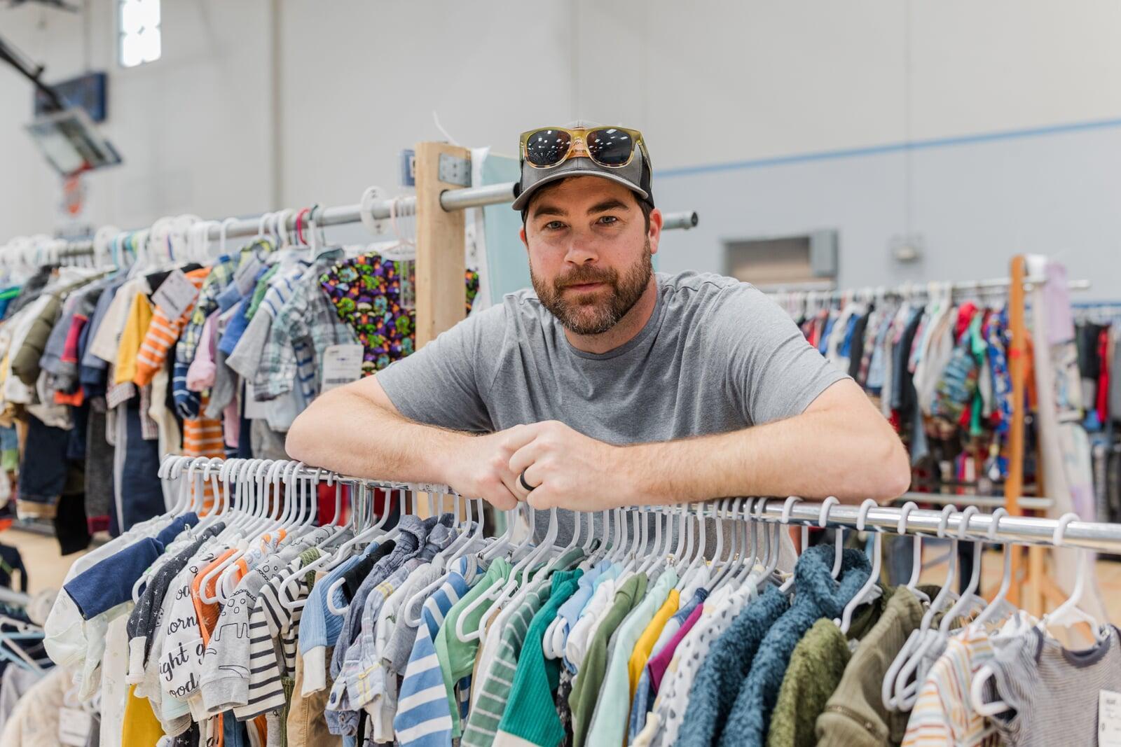 Two masked moms—one holding a child with a mask, the other pregnant—shop for their families at the local JBF sale.