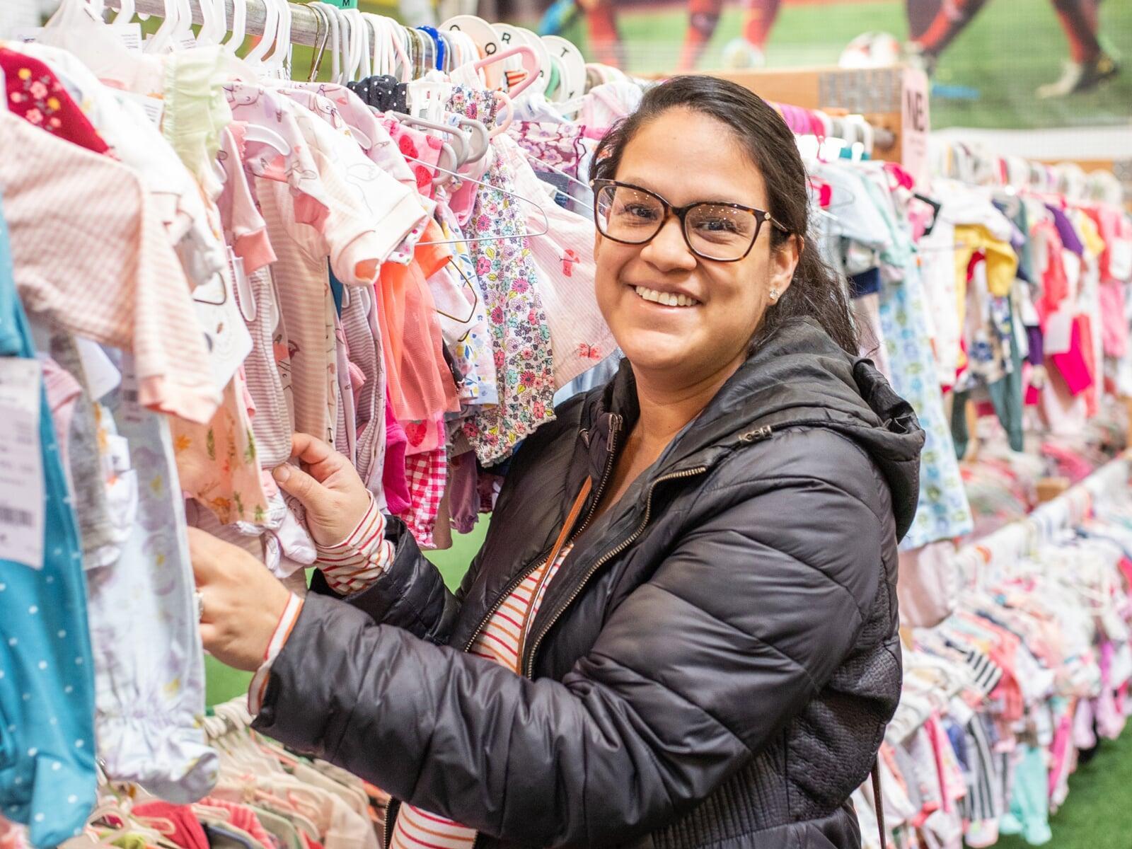 Mom holds daughter who is sleeping in her arms while she shops the local JBF sale.