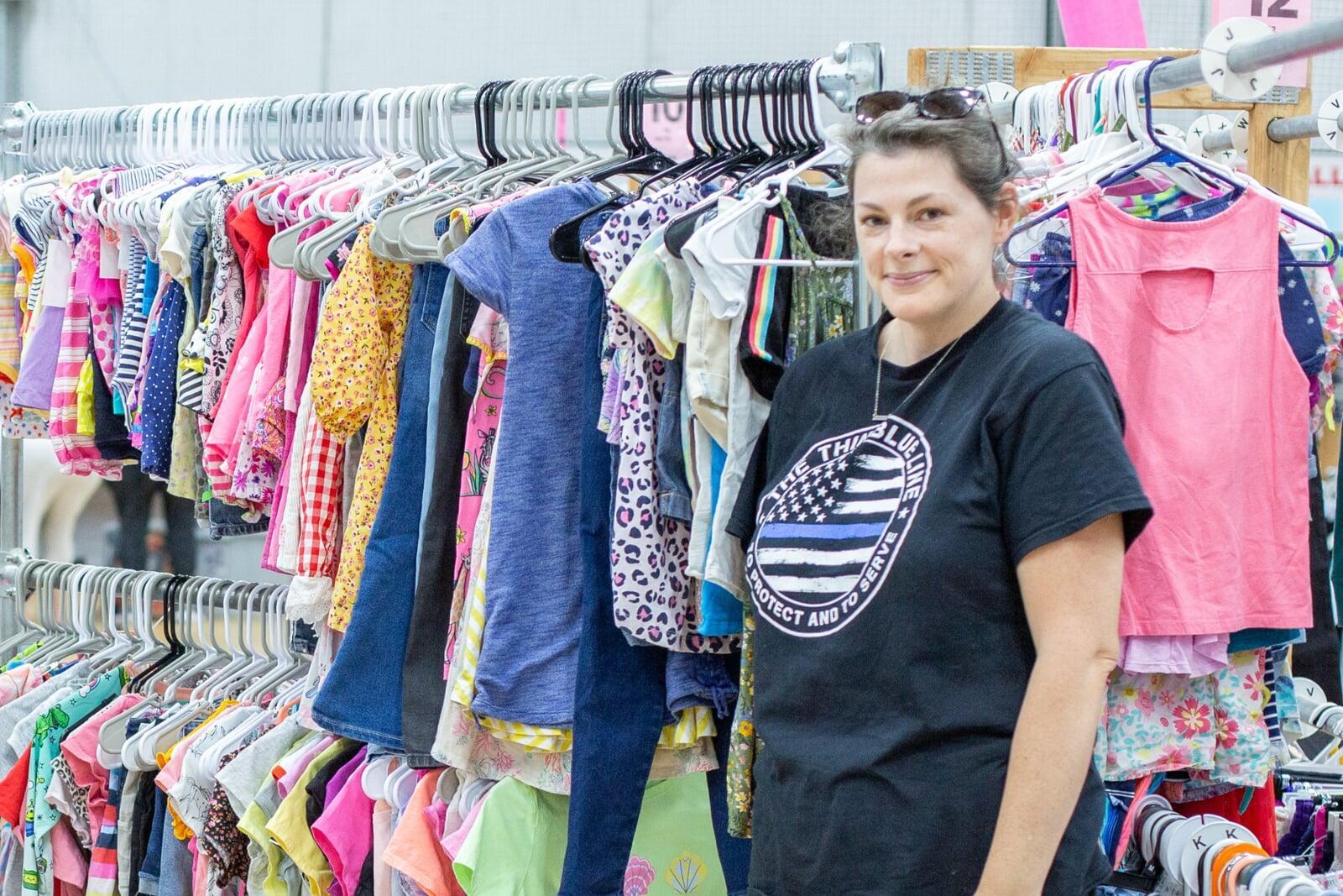 A woman consigning stands by her rack of clothing